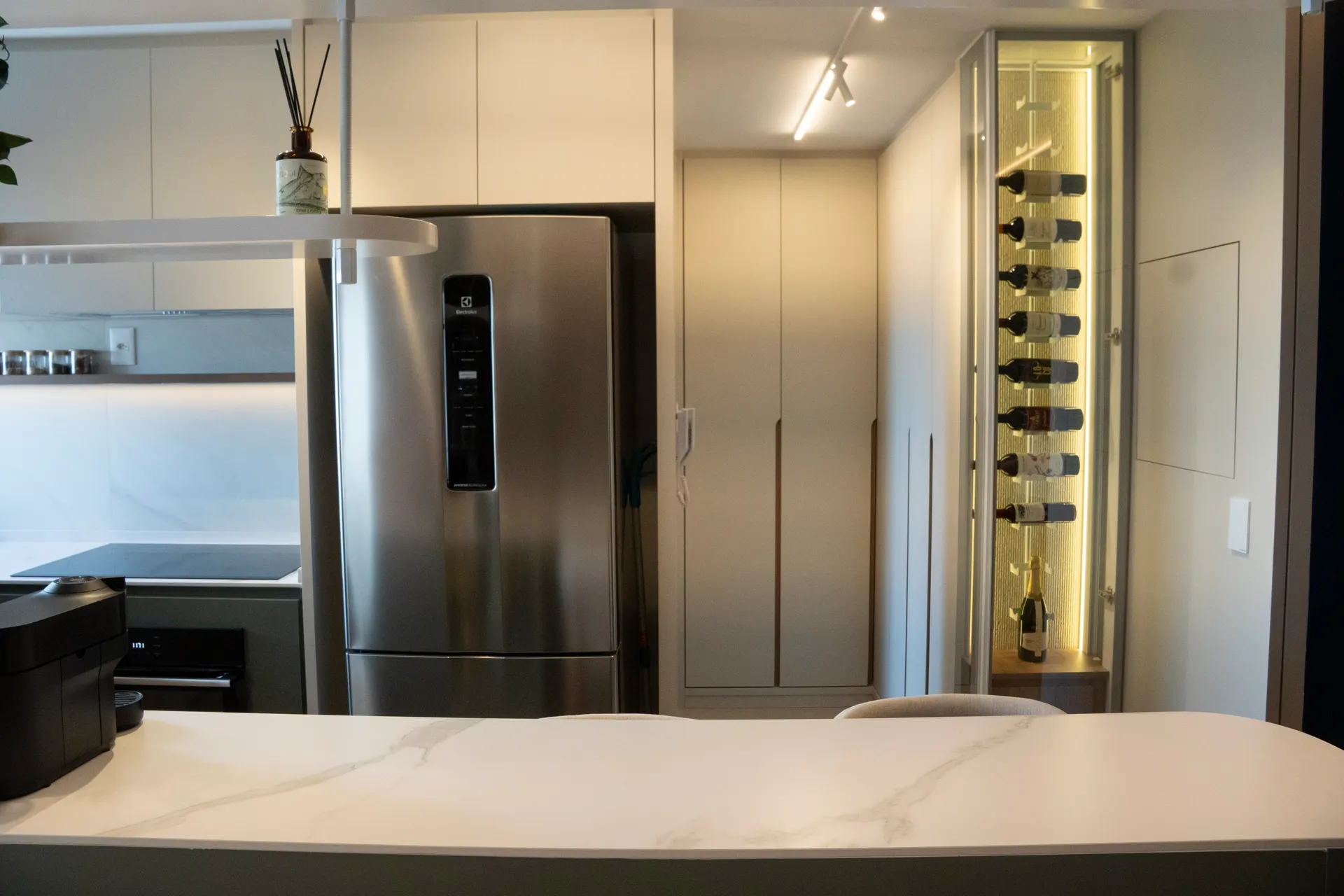 Cozinha com adega iluminada e geladeira inox